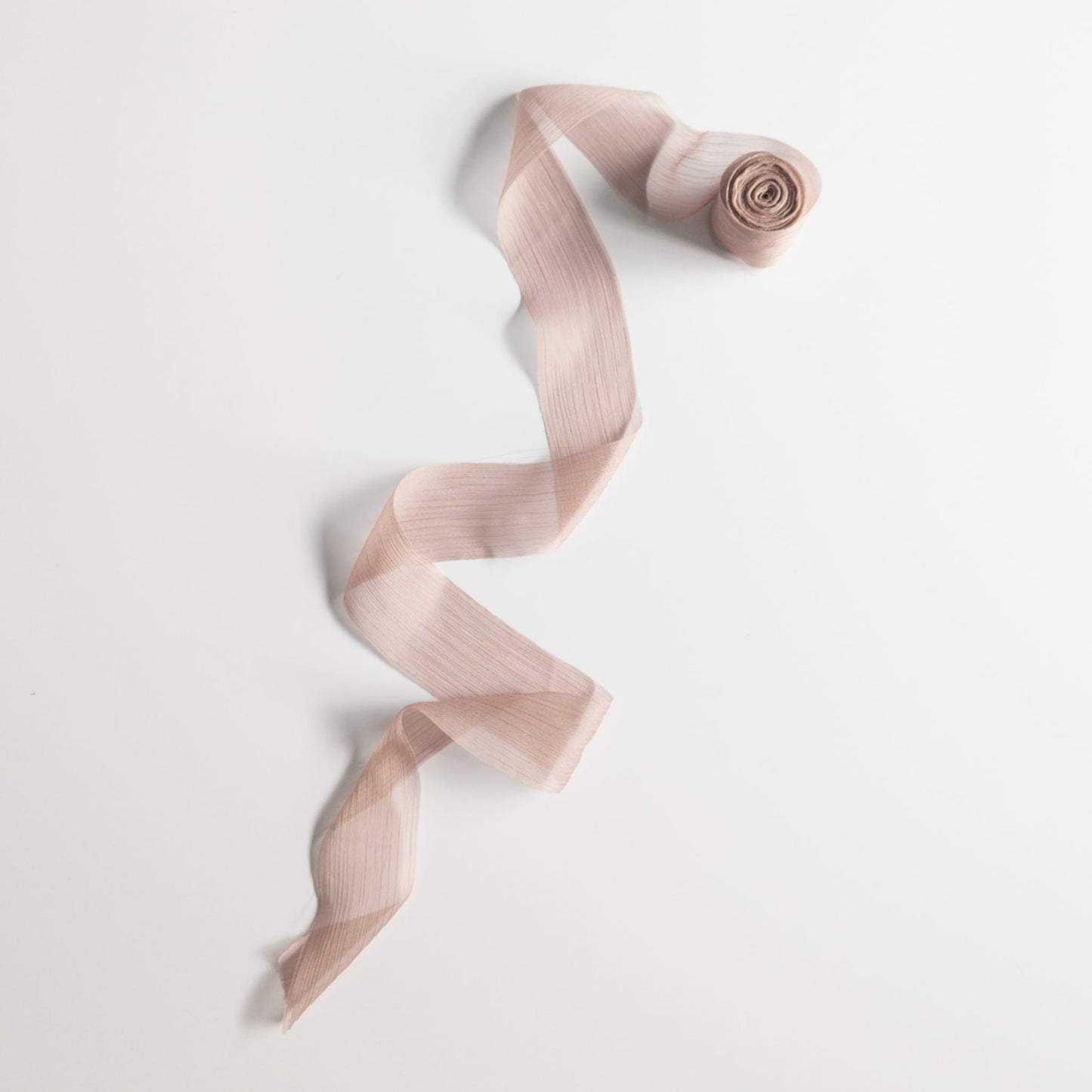 Soft pleated chiffon ribbon in blush pink draped elegantly.