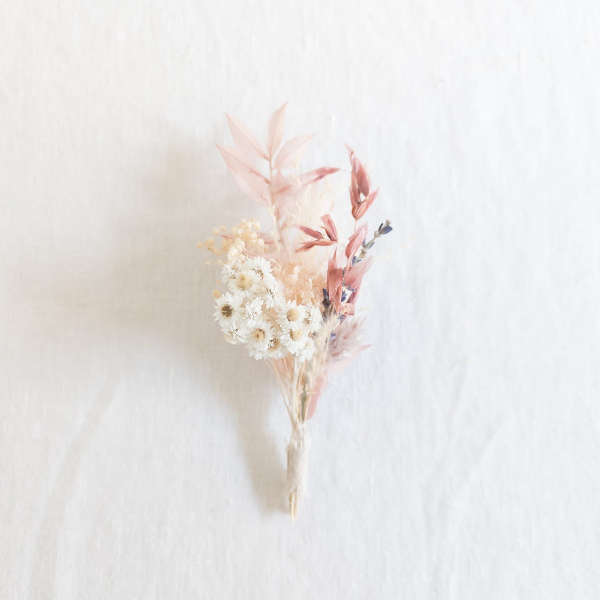 Mini bud vase bouquet with delicate flowers on a linen fabric background