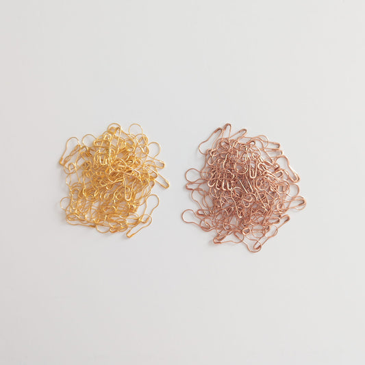 Flat lay of assorted safety pins with crafting and sewing supplies

